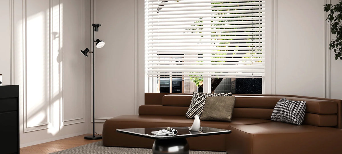 Black SIBRILLE three-head floor lamp beside a brown sofa in a bright living room