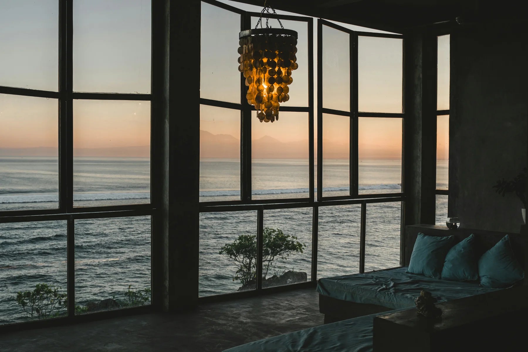 A warm hanging light by ocean-view windows